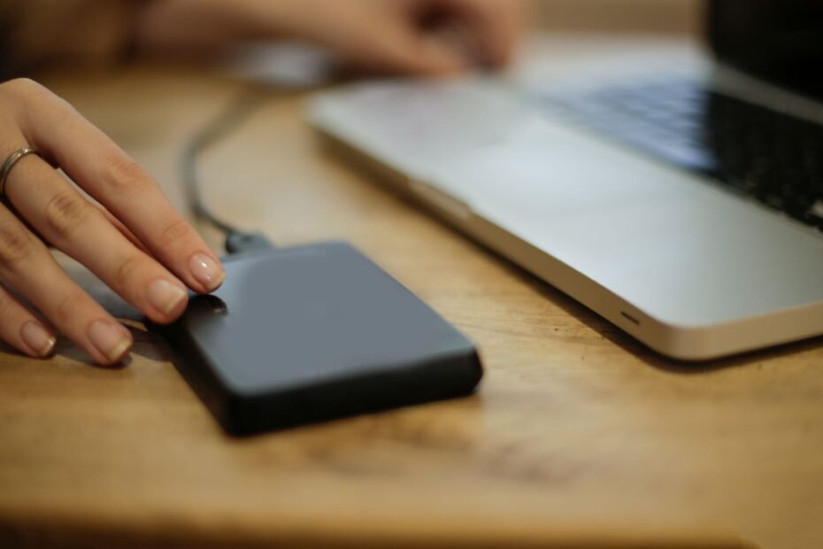Pessoa conectando HD externo a um laptop, ilustrando backup de site WordPress