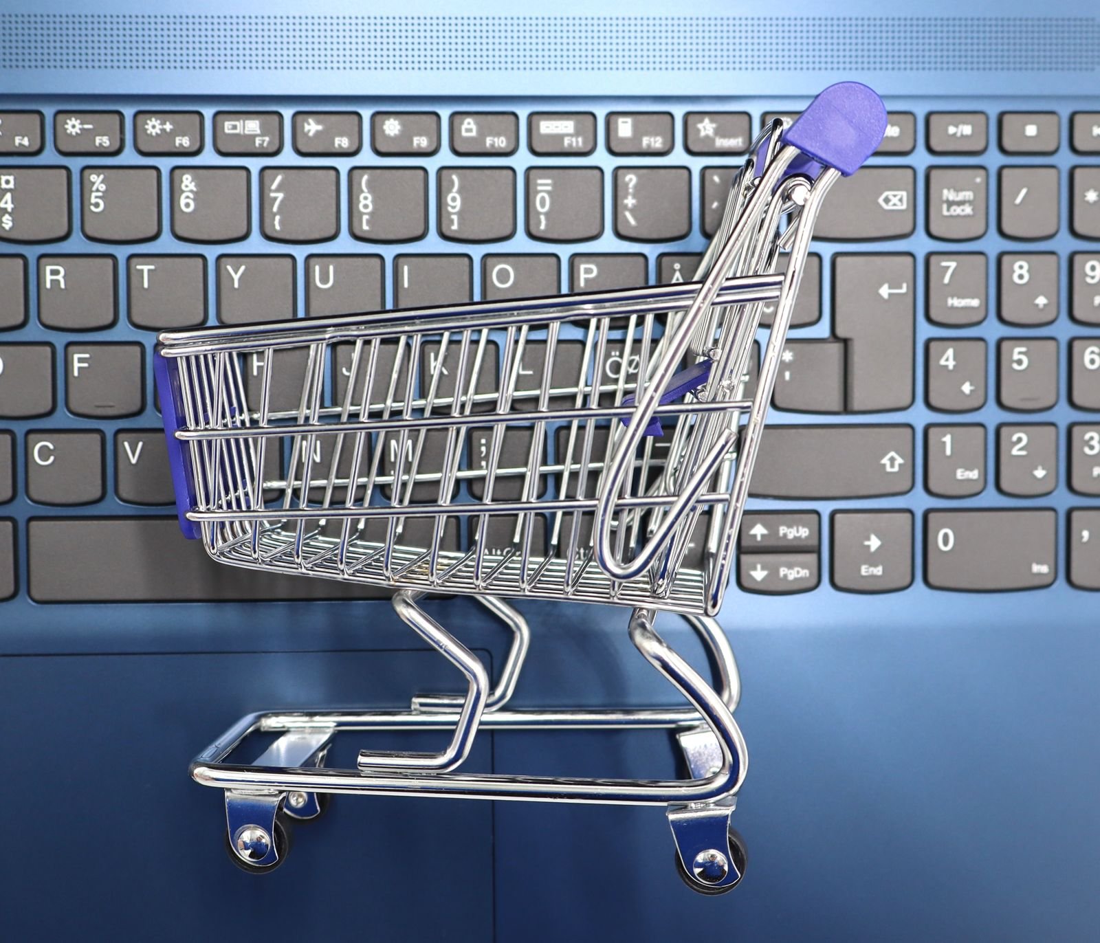 Carrinho de compras em miniatura sobre laptop, imagem ilustrativa