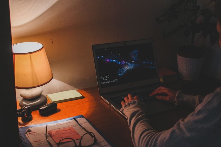 Pessoa em suéter cinza usando laptop, ilustrando como criar um infoproduto