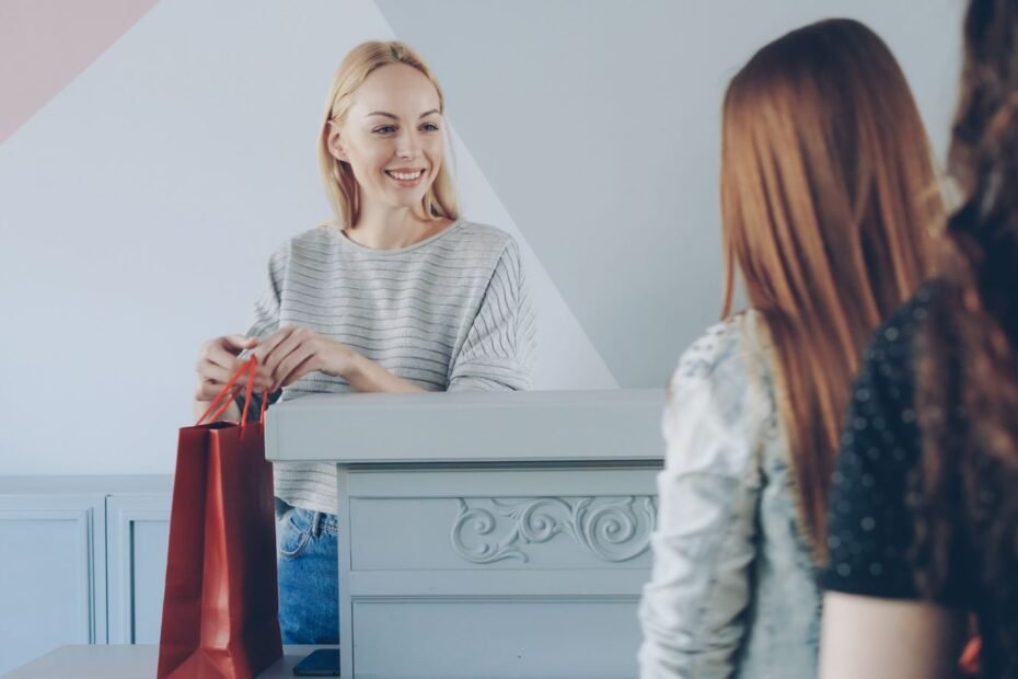Vendedora entregando sacola para clientes sorridentes em loja, ilustrando como fidelizar clientes