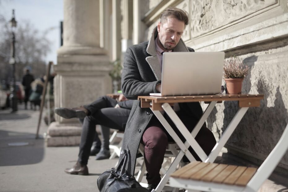 Freelancer de marketing digital trabalhando em laptop num espaço urbano ao ar livre