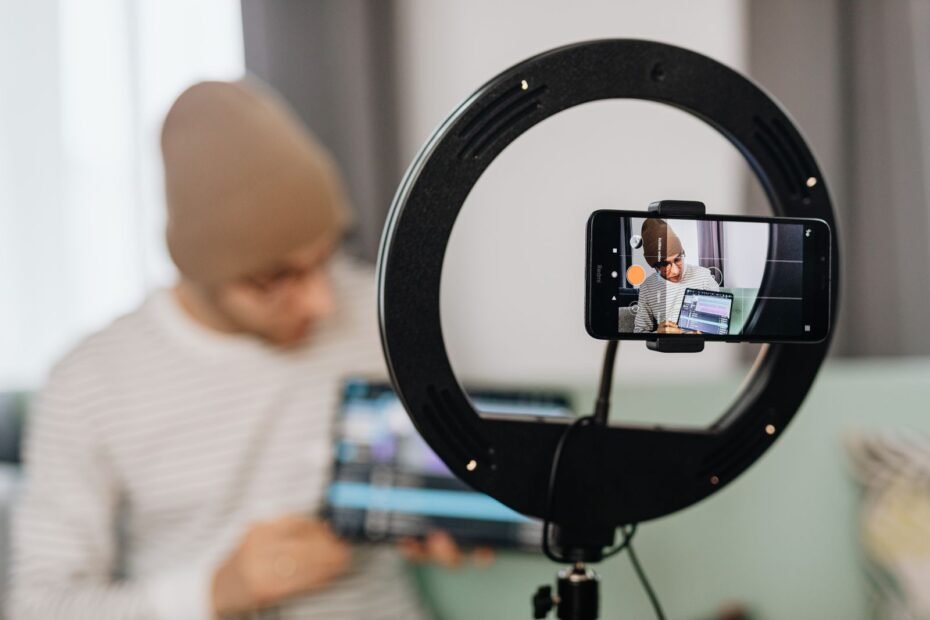 Homem gravando vídeo com ring light e smartphone, ilustrando como ganhar dinheiro nas redes sociais
