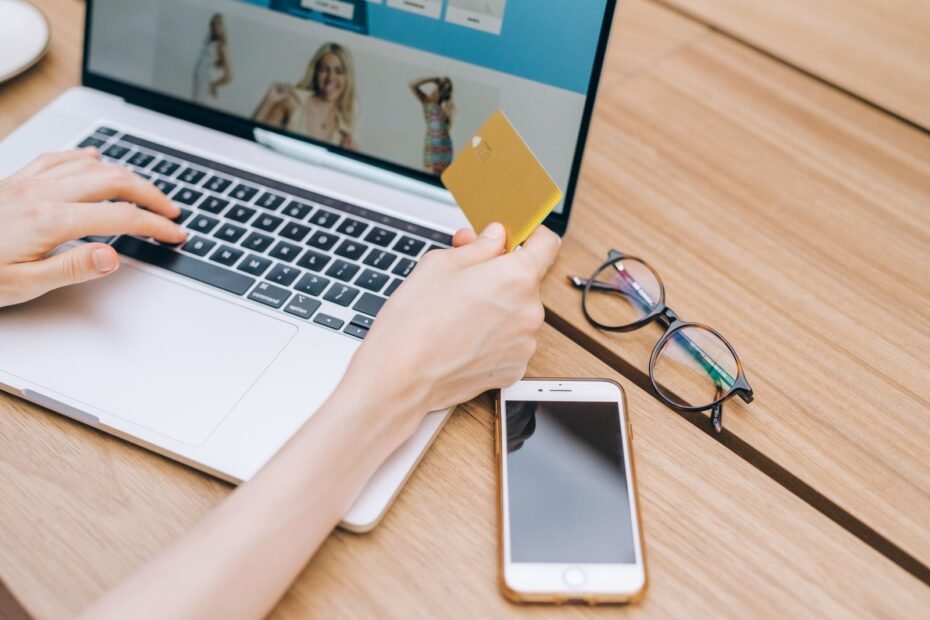 Consumidor finalizando compra online no laptop com cartão, exemplo de gatilhos mentais para vendas