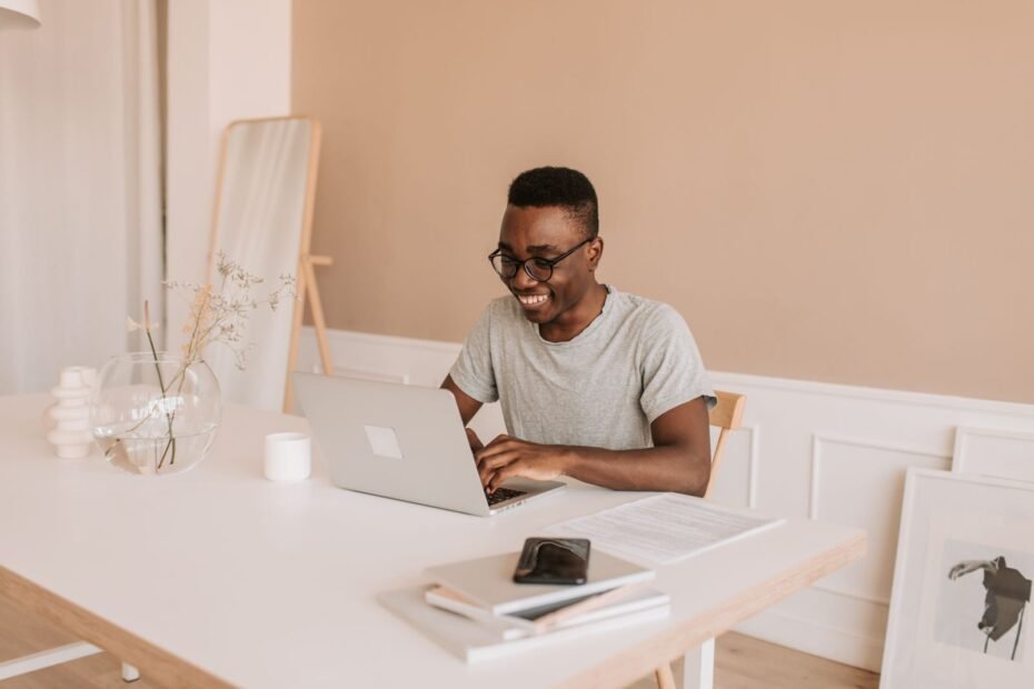Homem sorrindo digitando em laptop, ilustrando renda extra online